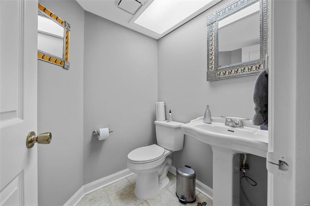half bath featuring baseboards, toilet, and a sink