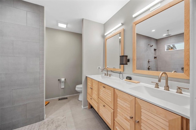 bathroom featuring a walk in shower, tile patterned floors, double vanity, toilet, and baseboards