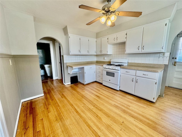 922 S 6th St, Belleville, IL 62220 - kitchen with white range with gas cooktop, arched walkways, light countertops, light wood-style floors, and tasteful backsplash