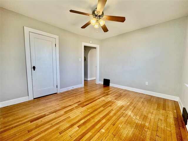 922 S 6th St, Belleville, IL 62220 - unfurnished bedroom featuring baseboards, arched walkways, light wood-type flooring, and ceiling fan