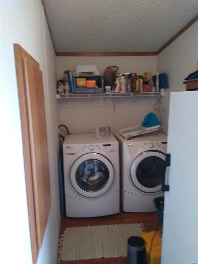 laundry area featuring separate washer and dryer, a textured ceiling, wood finished floors, and ornamental molding