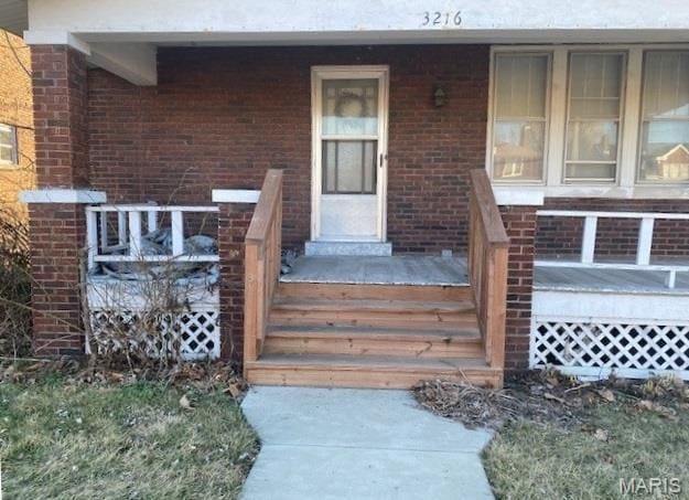 entrance to property with covered porch and brick siding