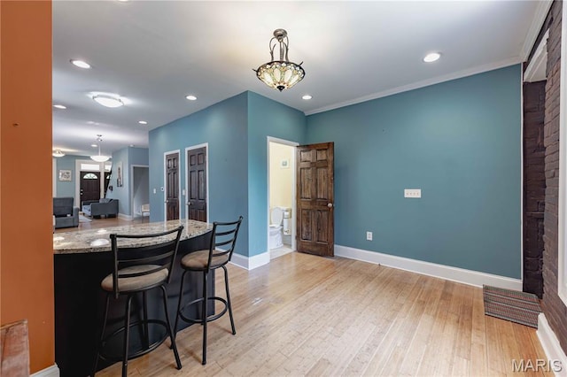 2244 Nebraska Ave, Saint Louis, MO 63104 - kitchen with light wood-type flooring, pendant lighting, recessed lighting, light stone countertops, and a breakfast bar