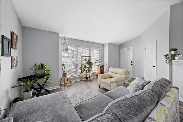 living room featuring wood finished floors, lofted ceiling, and baseboards