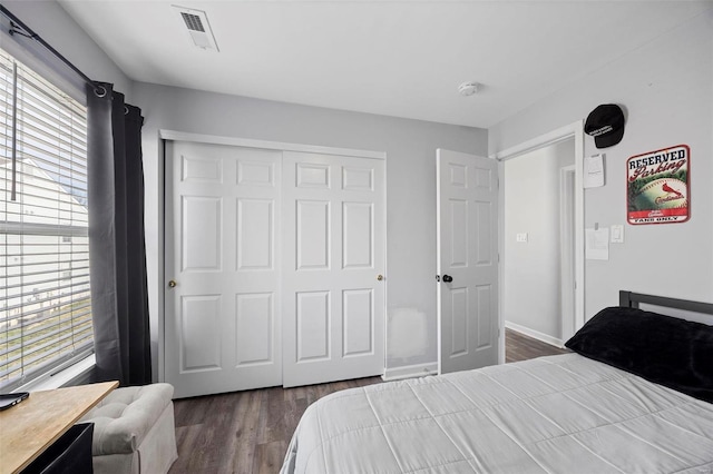 bedroom featuring dark wood-type flooring, a closet, and baseboards