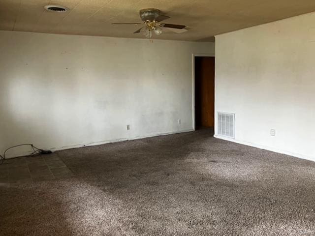 spare room featuring a ceiling fan and dark carpet