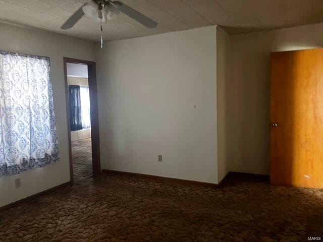 carpeted spare room featuring a ceiling fan