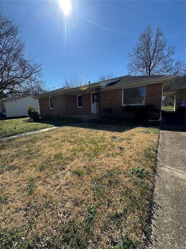 single story home with brick siding, a front yard, solar panels, and an attached carport
