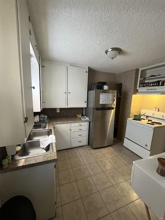 kitchen featuring white electric stove, freestanding refrigerator, white cabinetry, light tile patterned floors, and a textured ceiling