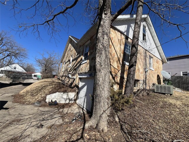 view of side of home with fence and stone siding