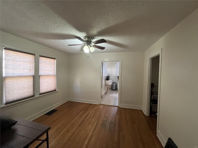 spare room featuring wood finished floors, a textured ceiling, ceiling fan, and baseboards