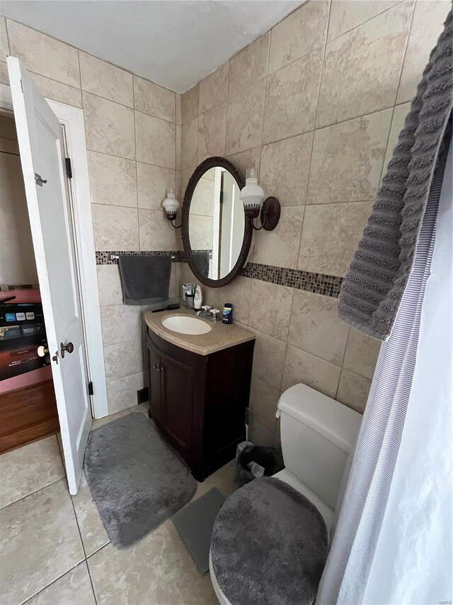 bathroom featuring tile walls, toilet, vanity, and tile patterned floors