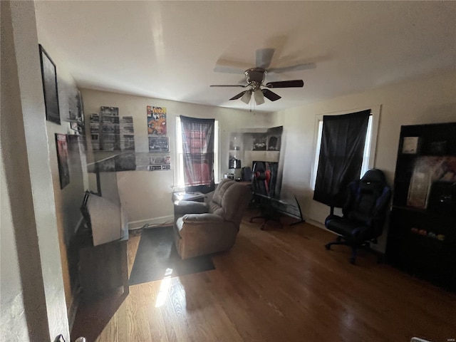 living area with wood finished floors, a ceiling fan, and baseboards