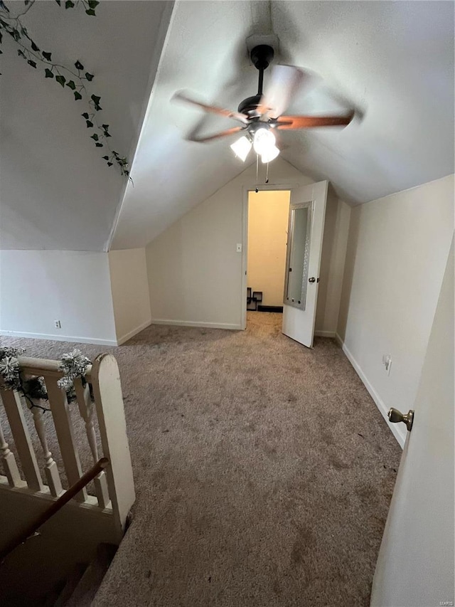 additional living space with a ceiling fan, light colored carpet, vaulted ceiling, and baseboards