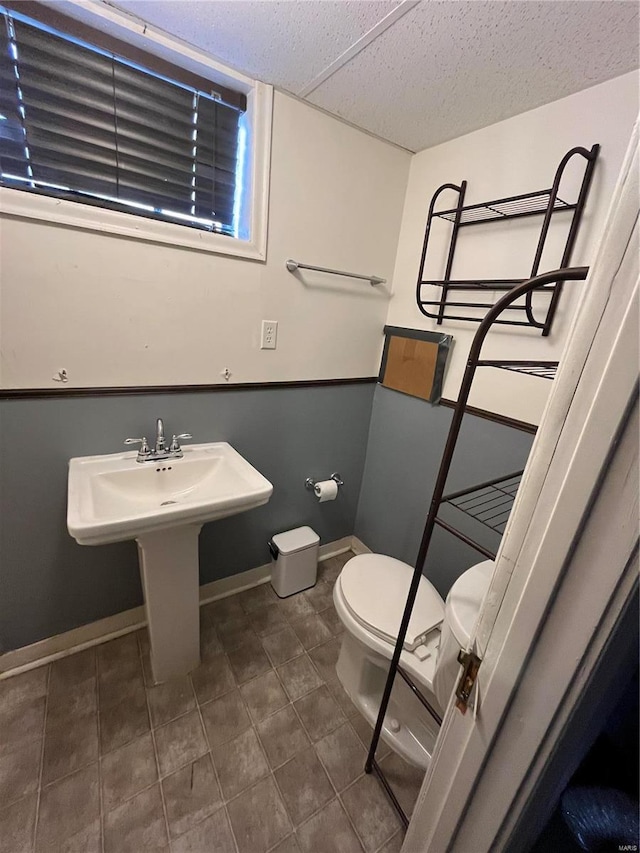 half bathroom with toilet, baseboards, and tile patterned flooring