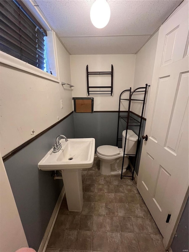 bathroom with toilet, baseboards, and a textured ceiling