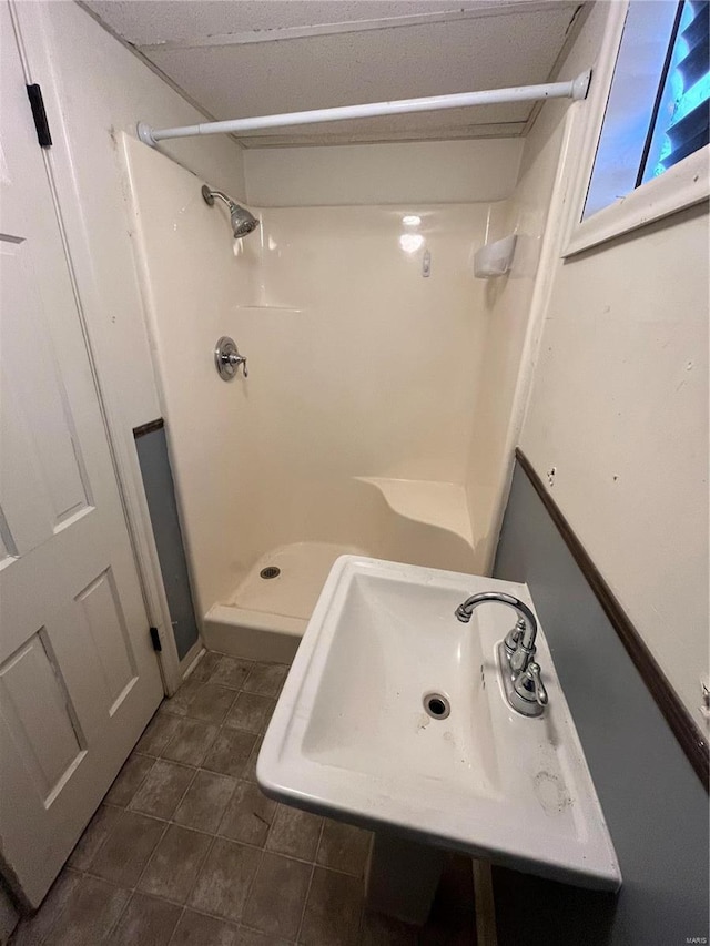 full bathroom featuring a stall shower, a sink, and tile patterned floors