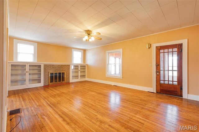 533 Locust St, Carrollton, IL 62016 - unfurnished living room featuring crown molding, wood finished floors, healthy amount of natural light, a ceiling fan, and a fireplace