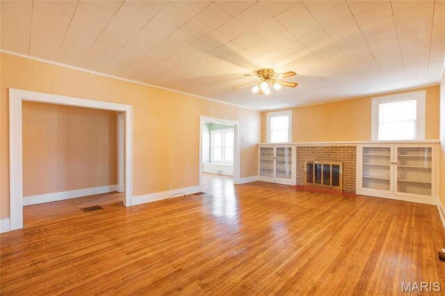 533 Locust St, Carrollton, IL 62016 - unfurnished living room with wood finished floors, ornamental molding, a ceiling fan, baseboards, and a brick fireplace