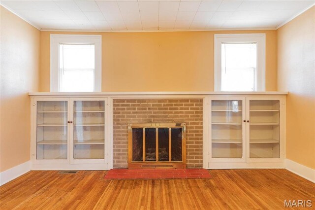 533 Locust St, Carrollton, IL 62016 - unfurnished living room featuring wood finished floors, baseboards, crown molding, and a brick fireplace