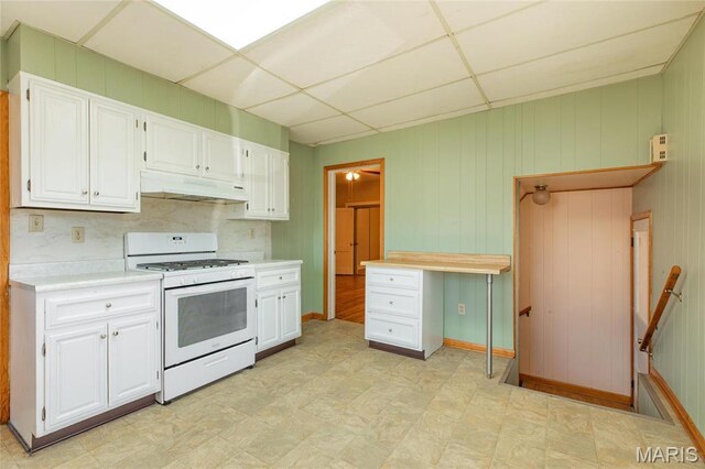533 Locust St, Carrollton, IL 62016 - kitchen featuring white gas stove, under cabinet range hood, light countertops, white cabinets, and a drop ceiling