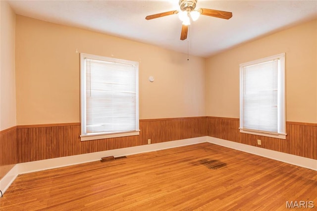 533 Locust St, Carrollton, IL 62016 - unfurnished room with wainscoting, healthy amount of natural light, wood finished floors, wood walls, and ceiling fan