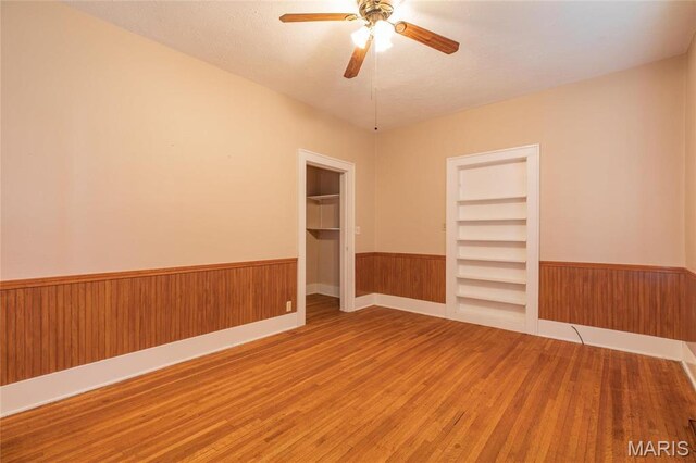 533 Locust St, Carrollton, IL 62016 - spare room with wainscoting, wood finished floors, ceiling fan, and wood walls