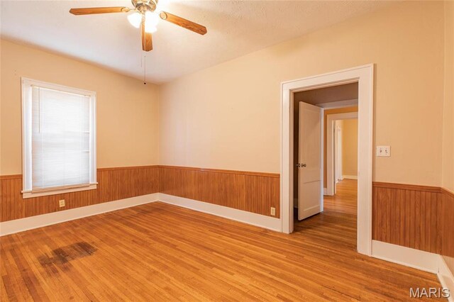 533 Locust St, Carrollton, IL 62016 - empty room with wainscoting, light wood-style floors, ceiling fan, and wooden walls