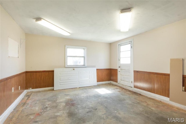533 Locust St, Carrollton, IL 62016 - unfurnished room with wainscoting, wood walls, healthy amount of natural light, and concrete floors