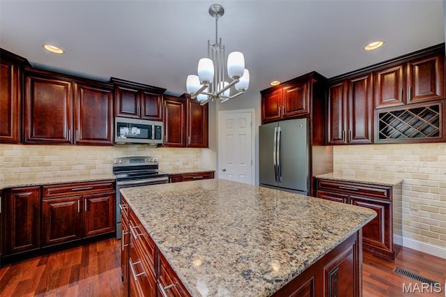 322 Gerard Ln, Moscow Mills, MO 63362 - kitchen with stainless steel appliances, reddish brown cabinets, a chandelier, dark wood-style flooring, and recessed lighting