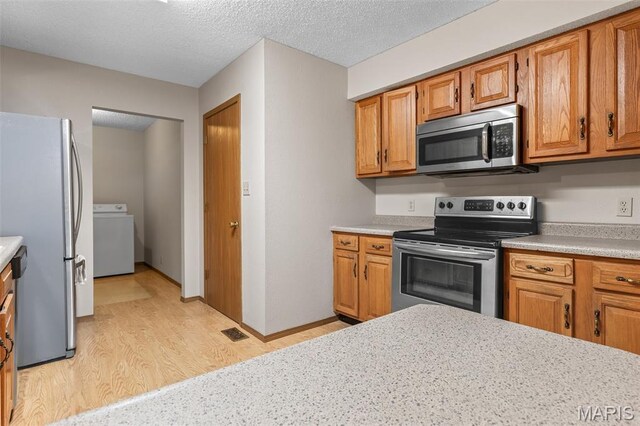 423 Rice Rd, Bonne Terre, MO 63628 - kitchen with stainless steel appliances, washer / clothes dryer, light wood finished floors, light countertops, and a textured ceiling