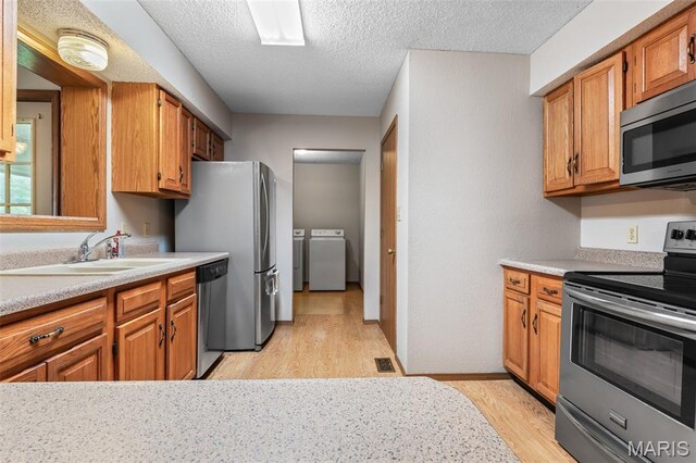 423 Rice Rd, Bonne Terre, MO 63628 - kitchen with appliances with stainless steel finishes, washing machine and clothes dryer, a sink, light wood-type flooring, and light countertops
