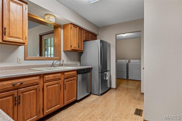 423 Rice Rd, Bonne Terre, MO 63628 - kitchen featuring appliances with stainless steel finishes, a sink, washer and dryer, light wood-style flooring, and brown cabinets