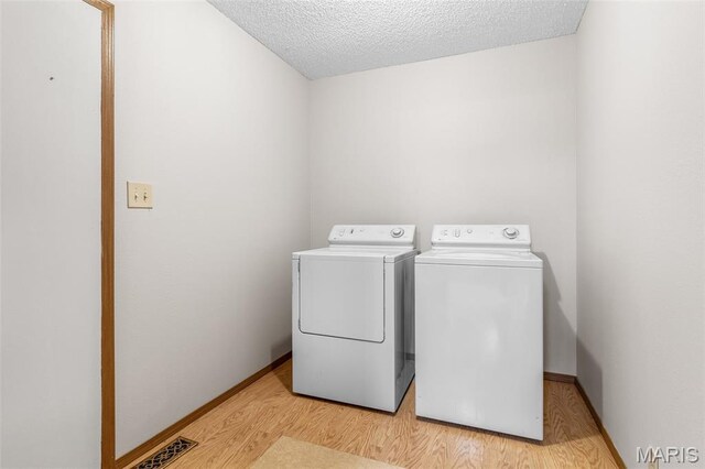 423 Rice Rd, Bonne Terre, MO 63628 - laundry area featuring washing machine and clothes dryer, light wood-style floors, baseboards, and a textured ceiling