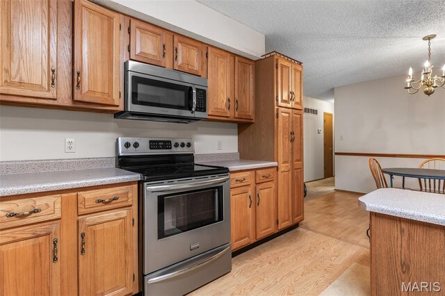 423 Rice Rd, Bonne Terre, MO 63628 - kitchen featuring appliances with stainless steel finishes, a chandelier, light countertops, light wood-style flooring, and brown cabinetry