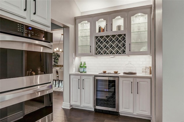 1155 Whitmoor Dr, Weldon Spring, MO 63304 - indoor dry bar featuring wine cooler, stainless steel double oven, backsplash, and dark wood-type flooring
