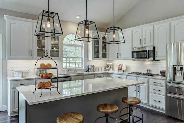 1155 Whitmoor Dr, Weldon Spring, MO 63304 - kitchen featuring stainless steel appliances, a sink, a breakfast bar, glass insert cabinets, and white cabinetry