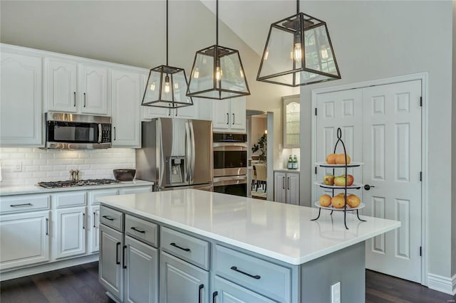 1155 Whitmoor Dr, Weldon Spring, MO 63304 - kitchen featuring appliances with stainless steel finishes, tasteful backsplash, dark wood finished floors, white cabinets, and vaulted ceiling