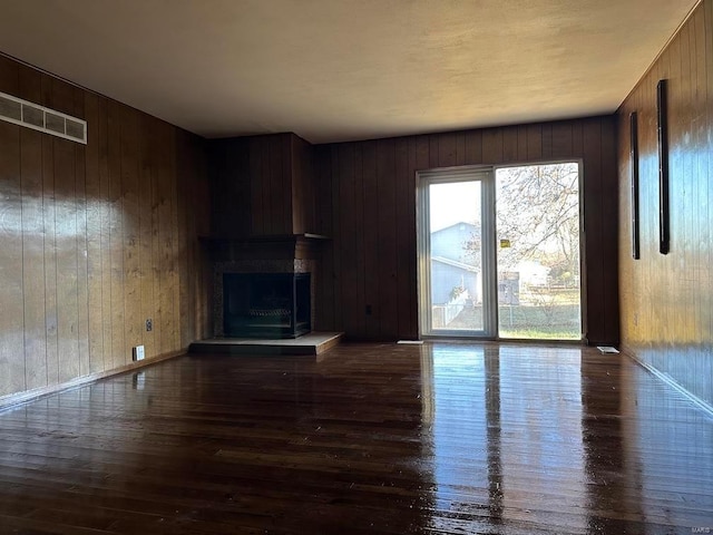 5220 Delcastle Dr, Florissant, MO 63034 - unfurnished living room featuring wood walls, dark wood-style flooring, and a fireplace with raised hearth