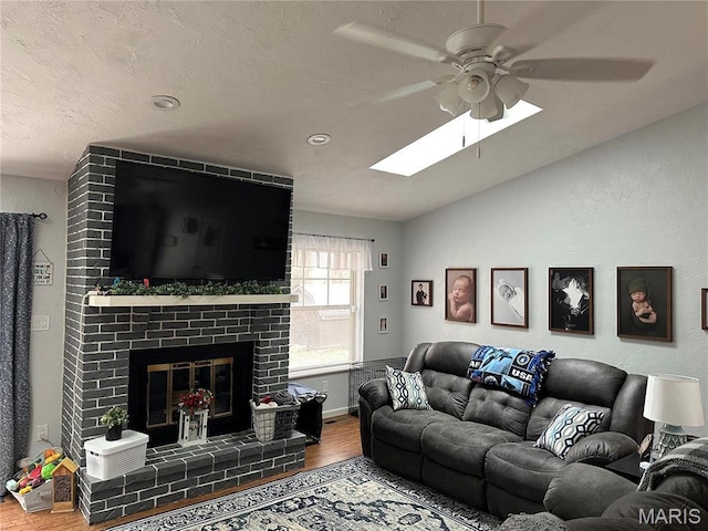 70 Innsbruck Ln, Shiloh, IL 62221 - living area featuring a ceiling fan, wood finished floors, a skylight, vaulted ceiling, and a brick fireplace