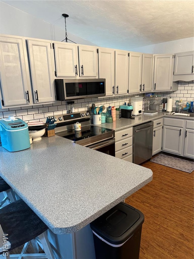 70 Innsbruck Ln, Shiloh, IL 62221 - kitchen featuring appliances with stainless steel finishes, tasteful backsplash, a breakfast bar area, a peninsula, and dark wood-style flooring