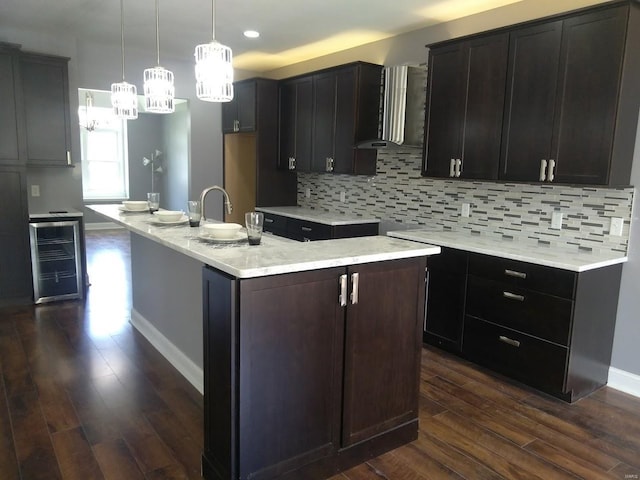 5835 Degiverville Ave, Saint Louis, MO 63112 - kitchen with wine cooler, wall chimney exhaust hood, dark wood-type flooring, a chandelier, and backsplash