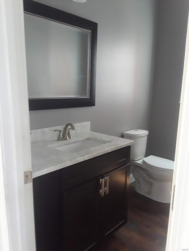 5835 Degiverville Ave, Saint Louis, MO 63112 - half bath with vanity, toilet, wood finished floors, and baseboards