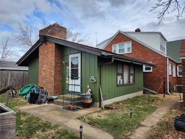view of front of house with a chimney, fence, board and batten siding, and entry steps