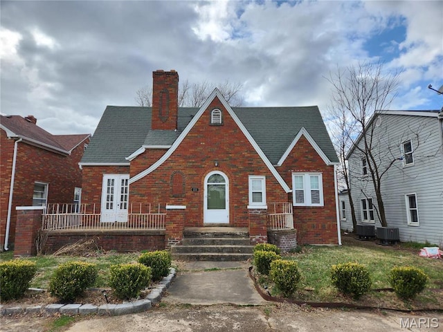 210 Linn St, Belle, MO 65013 - tudor-style house featuring brick siding, a chimney, a front lawn, and roof with shingles