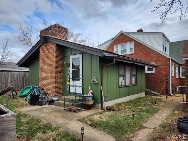 210 Linn St, Belle, MO 65013 - view of front of house featuring a chimney, board and batten siding, entry steps, and brick siding