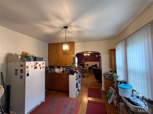 210 Linn St, Belle, MO 65013 - kitchen featuring freestanding refrigerator, arched walkways, brown cabinetry, light wood finished floors, and decorative light fixtures