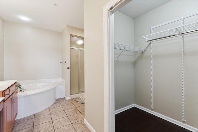 full bathroom featuring a shower stall, vanity, a spacious closet, and a bath