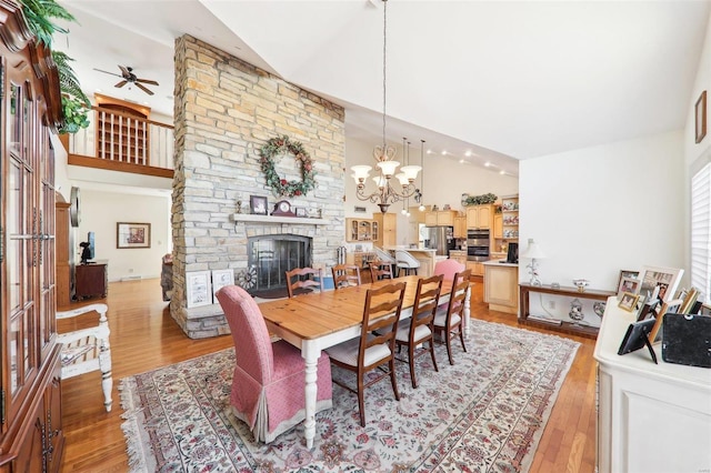 900 Deer Circle Dr, Carlyle, IL 62231 - dining area with a ceiling fan, a stone fireplace, light wood-type flooring, high vaulted ceiling, and a chandelier