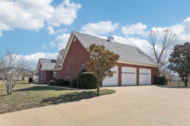 900 Deer Circle Dr, Carlyle, IL 62231 - view of side of home featuring driveway, a chimney, brick siding, an attached garage, and roof with shingles